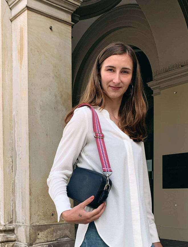 Roter Taschengurt an schwarzer Handtasche