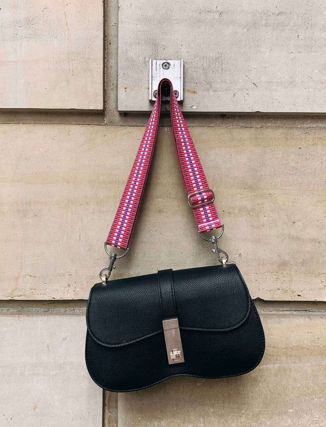 Roter Taschengurt an schwarzer Handtasche